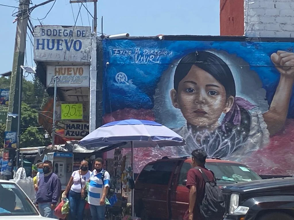 Calle de Cuernavaca con comercios de huevo y un mural de una niña.
