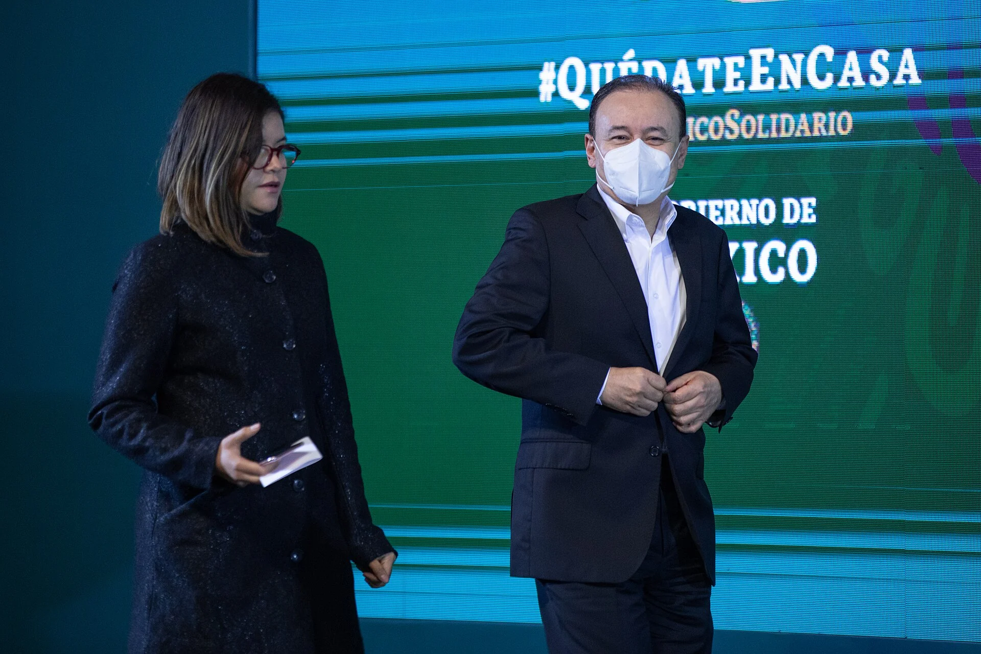 Alfonso Durazo con cubrebocas, junto a una mujer, durante una conferencia en 2020.